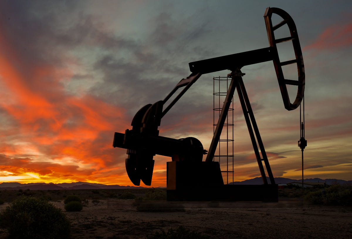 Oil field at dusk with a darkened pump jack to help illustrate IoT for oil and gas